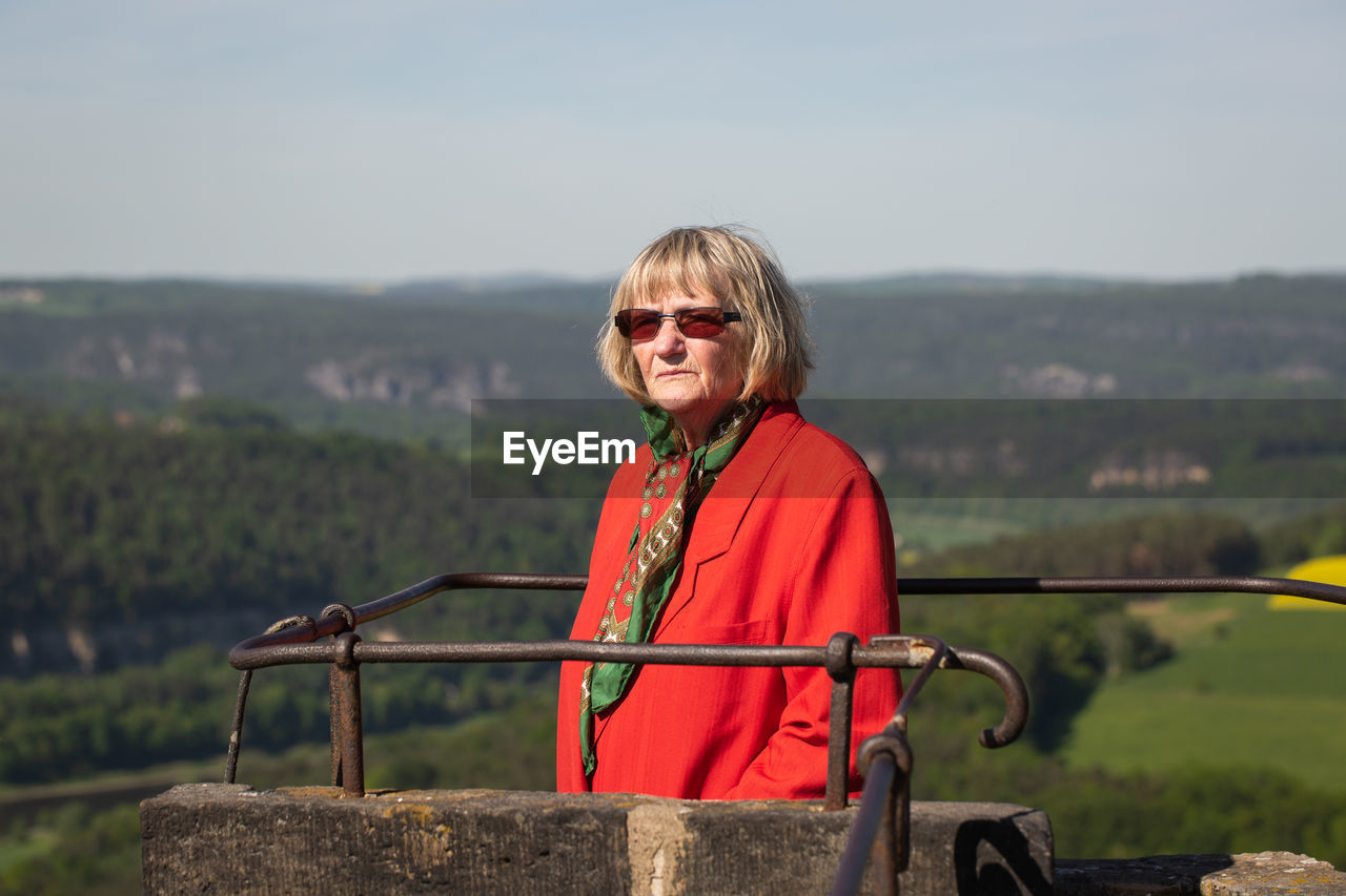 PORTRAIT OF WOMAN STANDING ON RAILING