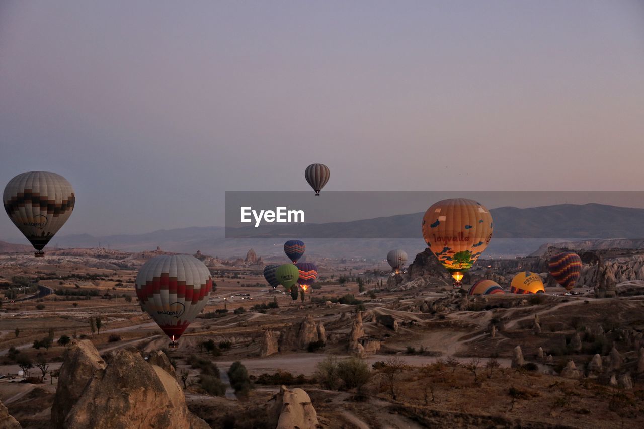 HOT AIR BALLOONS FLYING OVER ROCK FORMATION AGAINST SKY