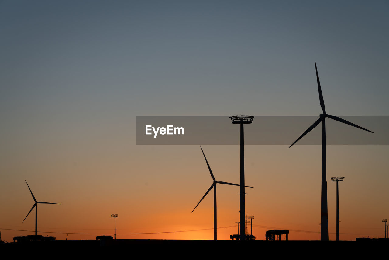 Silhouette of wind turbine against sky during sunset