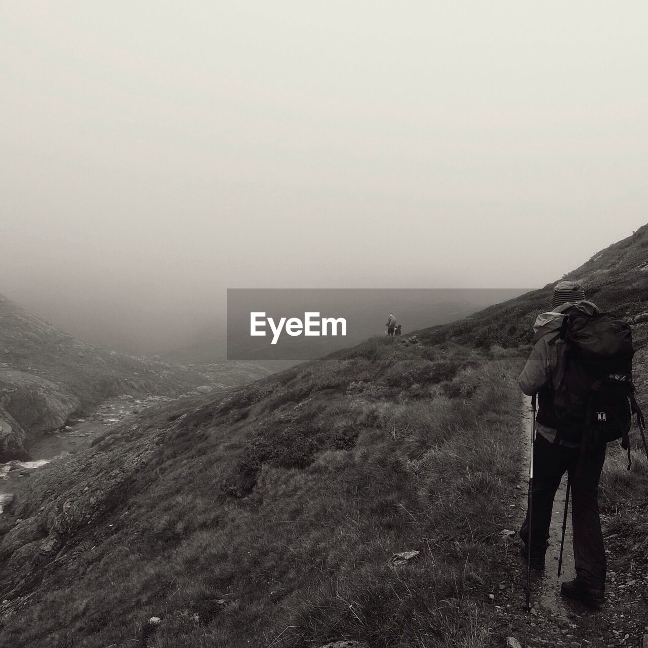 Rear view of hiker on mountain during foggy weather