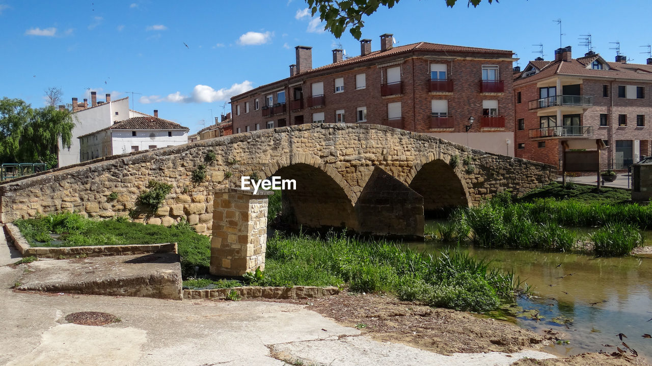 ARCH BRIDGE OVER RIVER AGAINST BUILDING