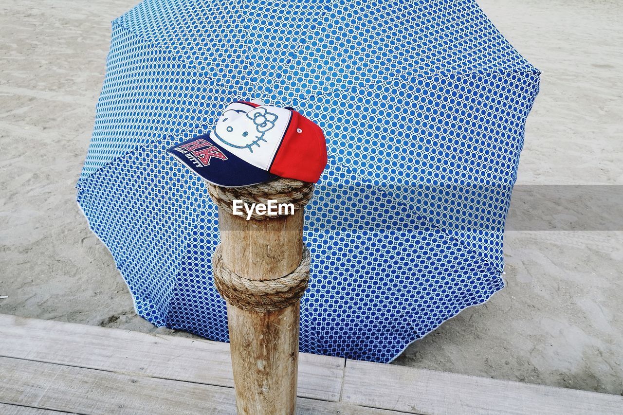 HIGH ANGLE VIEW OF UMBRELLA ON WOODEN POST