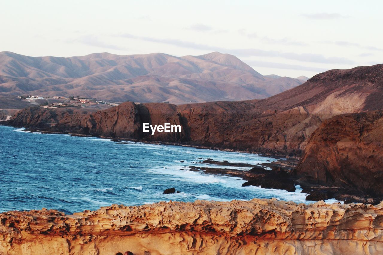 SCENIC VIEW OF SEA BY MOUNTAINS AGAINST SKY