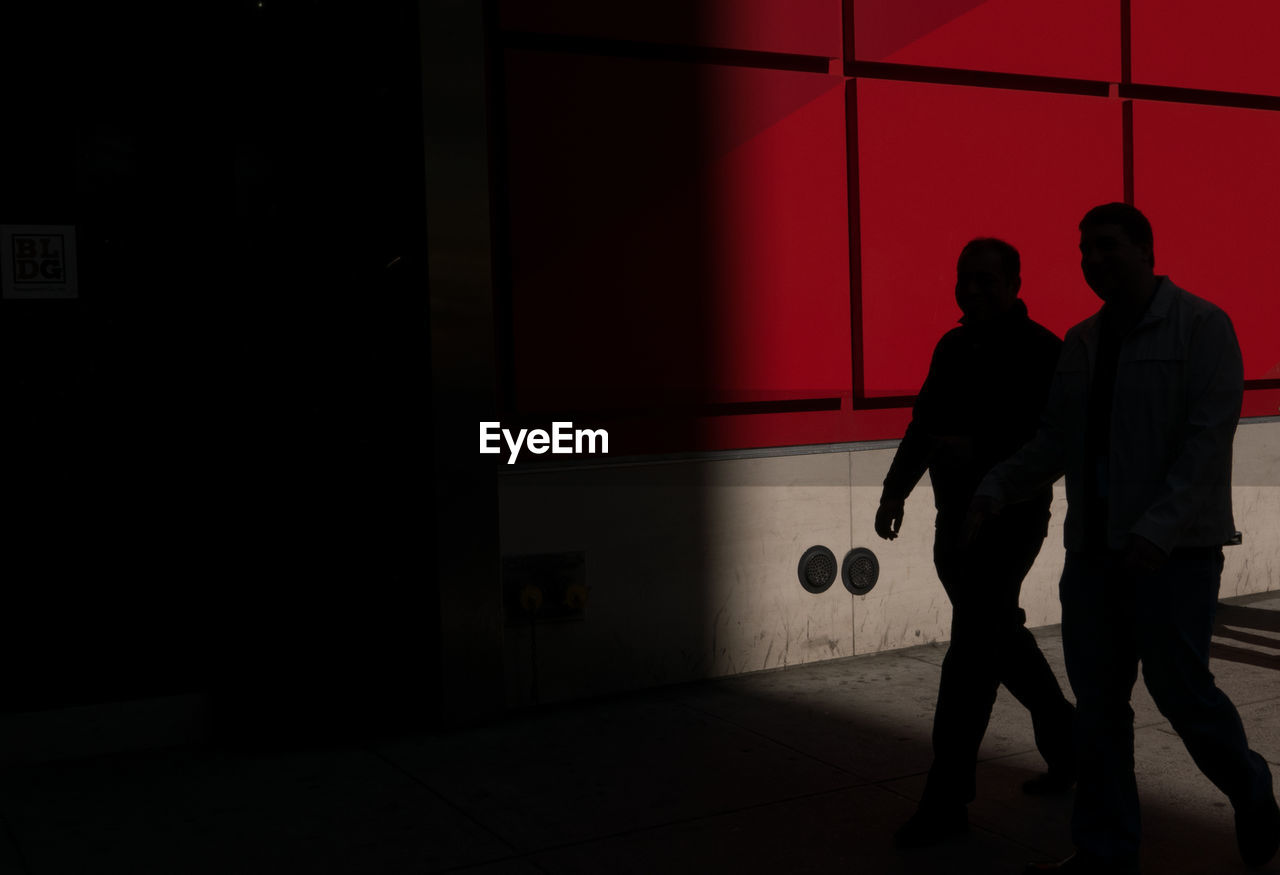 SILHOUETTE MAN AND WOMAN WALKING ON CORRIDOR OF BUILDING