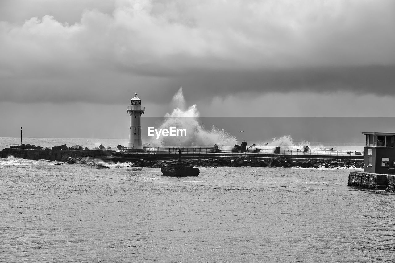 water, lighthouse, architecture, built structure, building exterior, sky, tower, cloud, sea, nature, coast, guidance, environment, black and white, industry, ocean, building, vehicle, no people, monochrome, smoke stack, factory, monochrome photography, day, pollution, beach, outdoors, wave, environmental issues, smoke, storm, air pollution, nautical vessel, transportation, breakwater, land