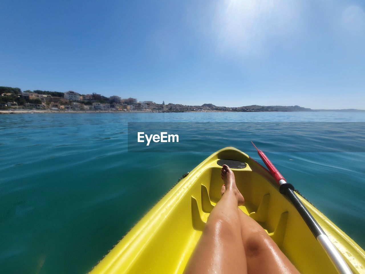 LOW SECTION OF PERSON ON YELLOW SEA AGAINST SKY