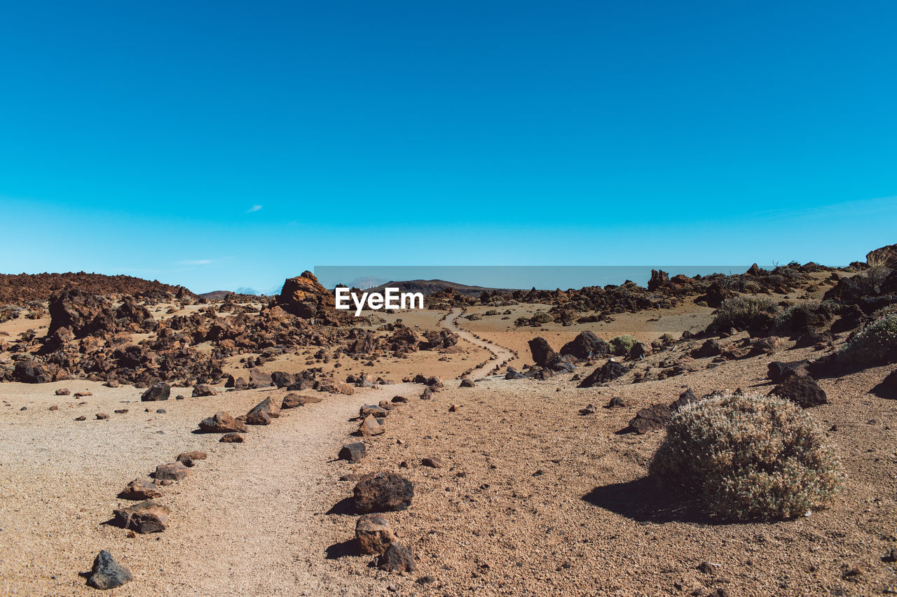 Scenic view of arid landscape against clear blue sky