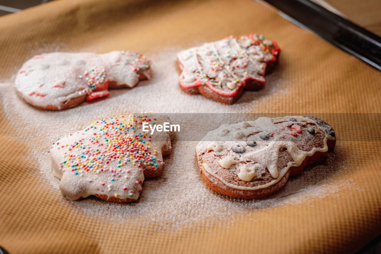 Christmas cookies sprinkled with icing sugar on a baking sheet.