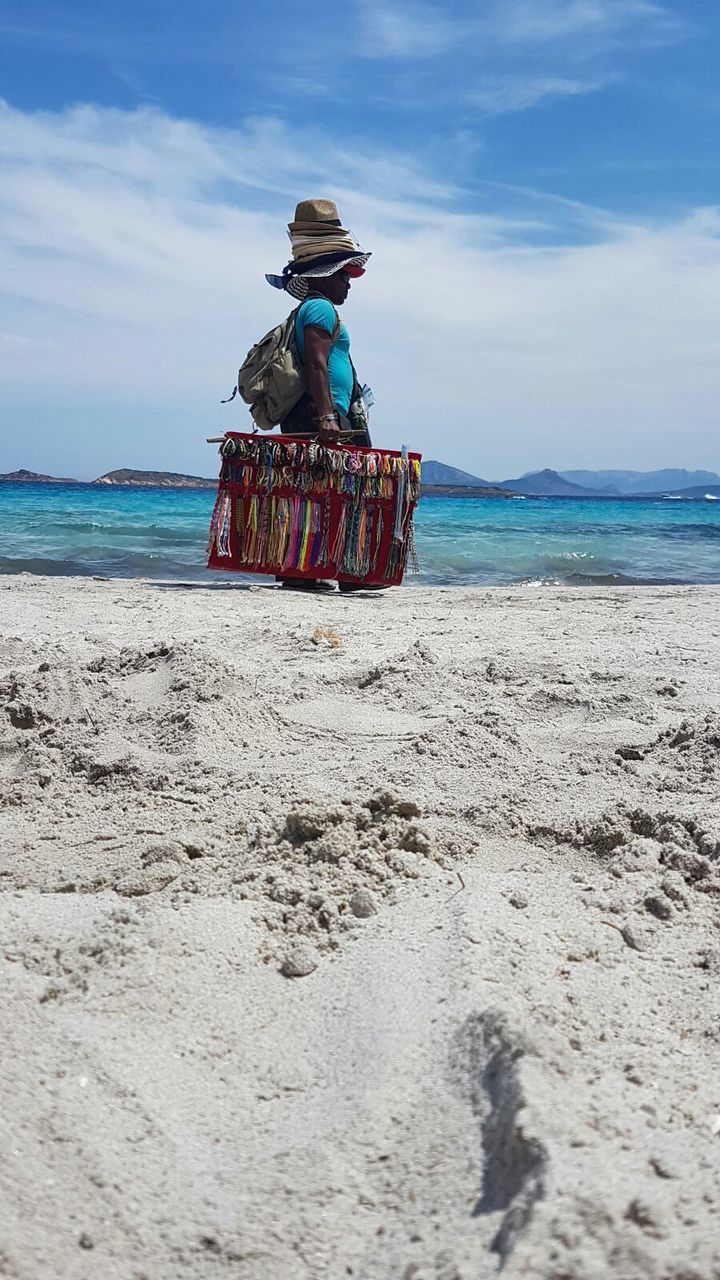 Man with hats and jewelry for sale at beach