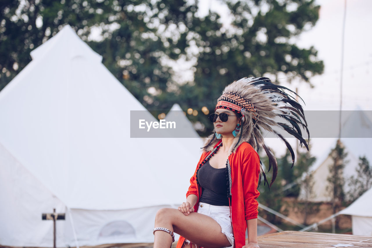 Young woman wearing headdress while sitting on picnic table