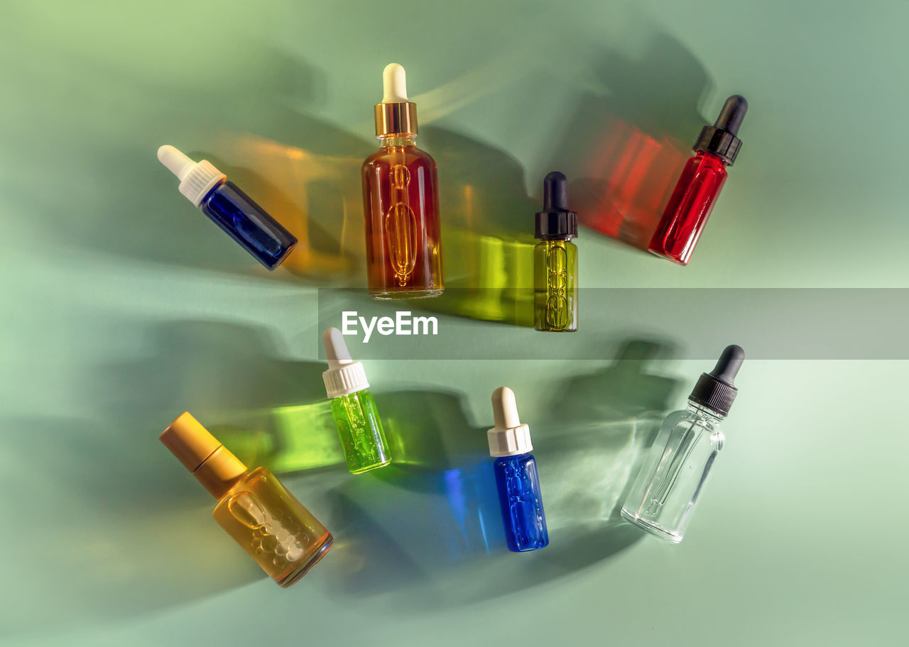 Transparent glass dropper bottles with colorful liquids on green background. cosmetics, healthcare