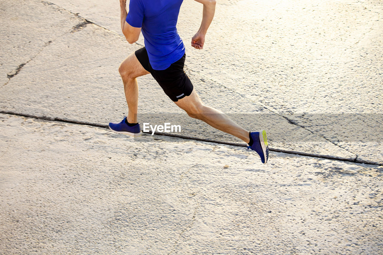 Low section of man walking on road