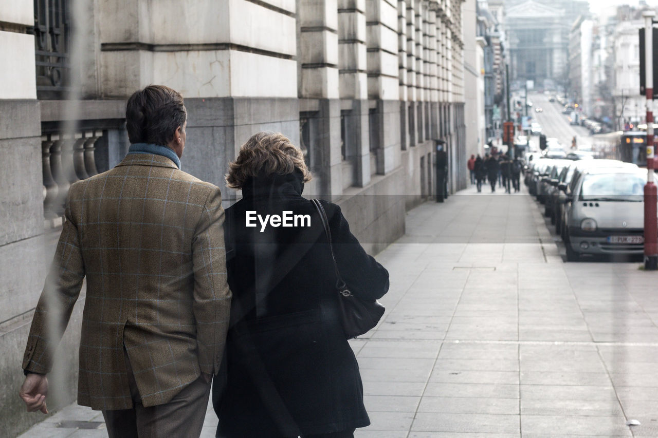 REAR VIEW OF PEOPLE ON STREET IN CITY