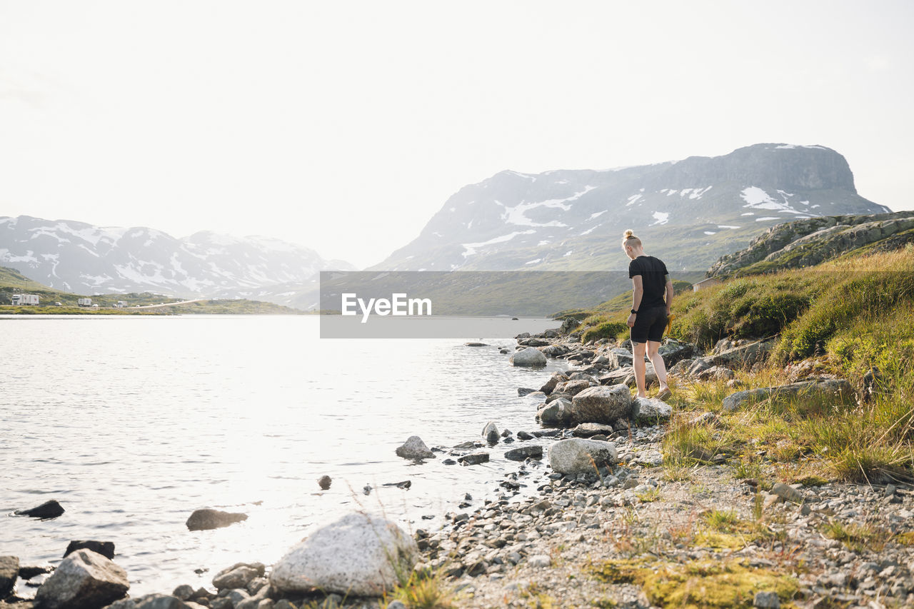 Woman standing at lake in mountains