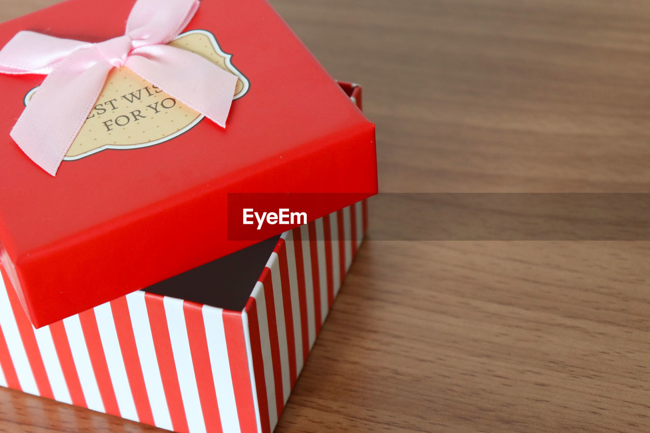 HIGH ANGLE VIEW OF RED BOX ON WOODEN TABLE