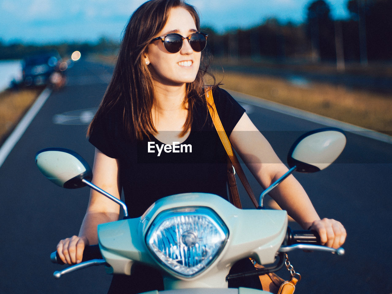 Young woman sitting on motor scooter at road