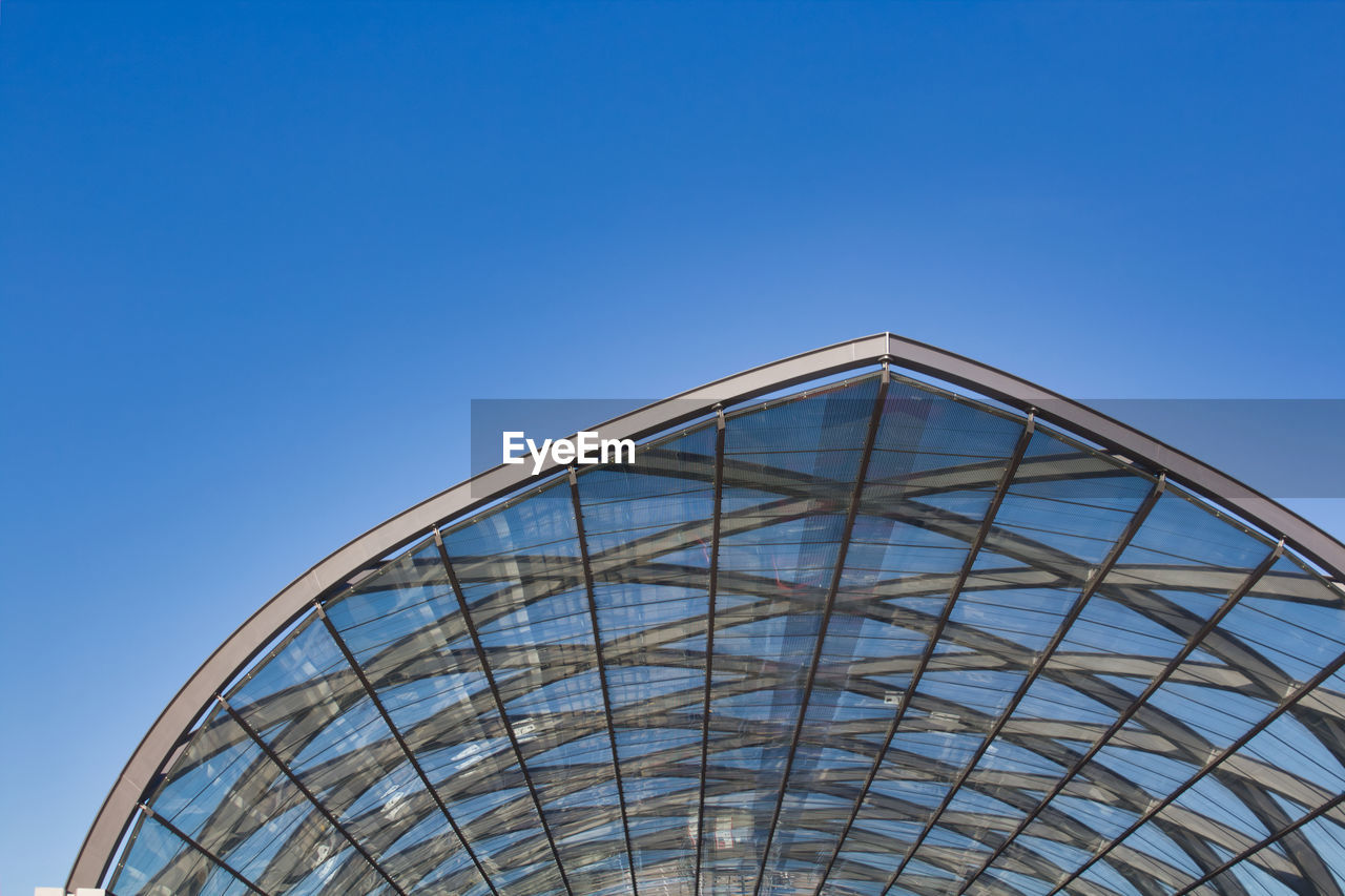 Low angle view of glass building against clear blue sky