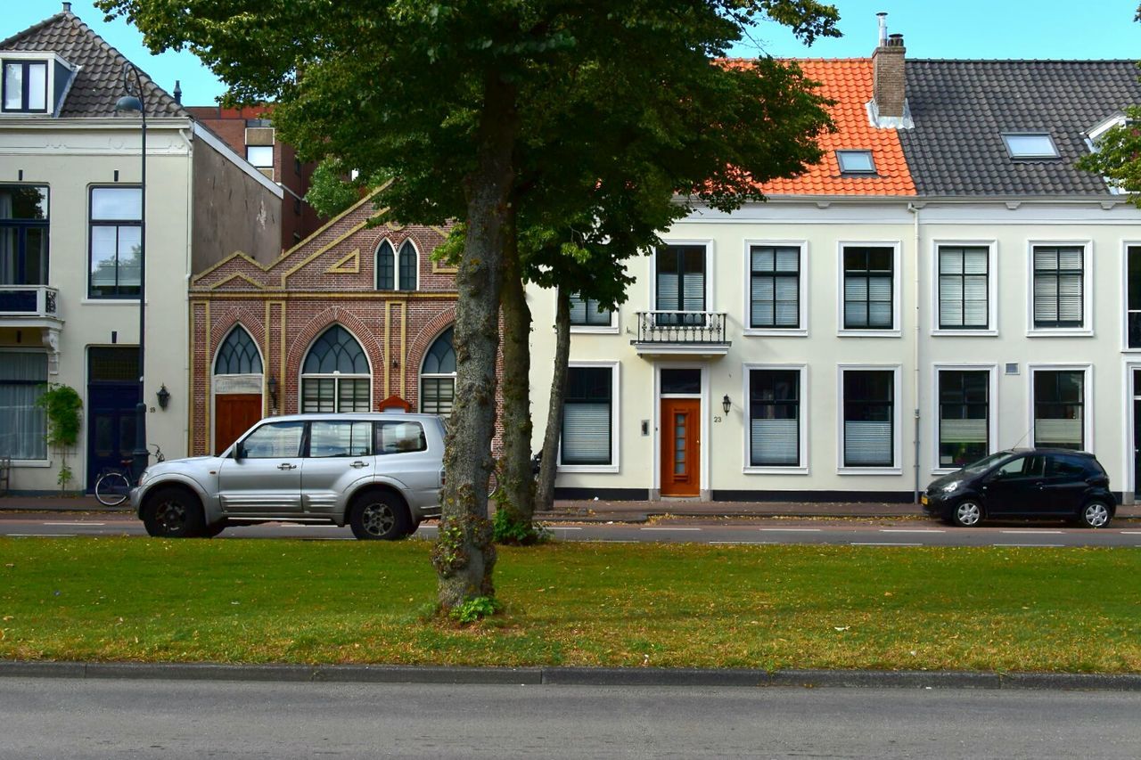 CARS PARKED ON ROAD IN FRONT OF BUILDINGS