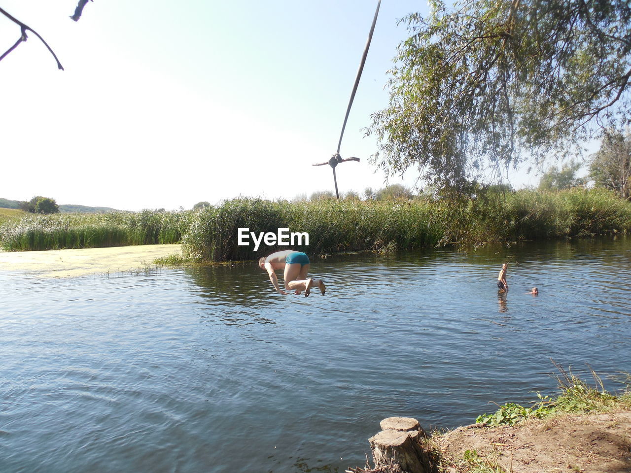 REAR VIEW OF MAN AND WOMAN FLYING OVER LAKE