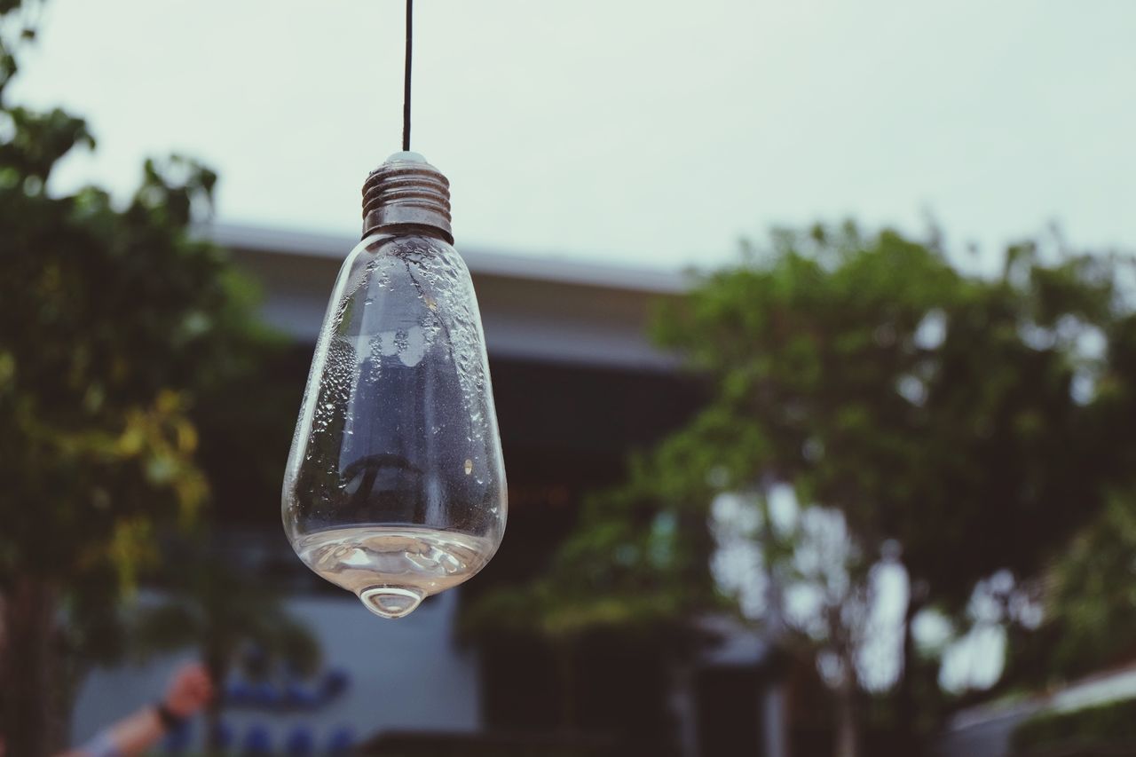 Close-up of light bulb hanging against sky