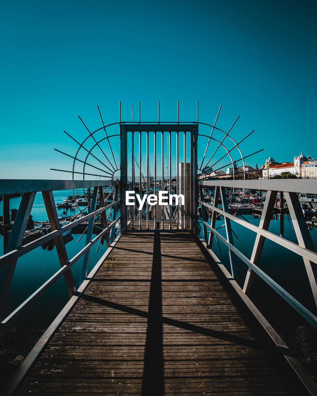 Pier over sea against clear blue sky