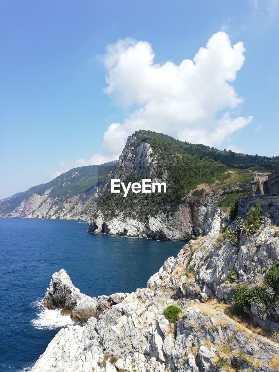 Scenic view of sea, mountains, and a rocky coastline against sky