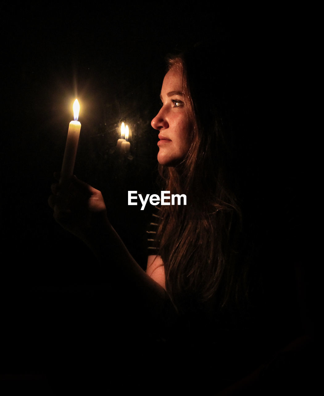 Woman holding lit candles in darkroom