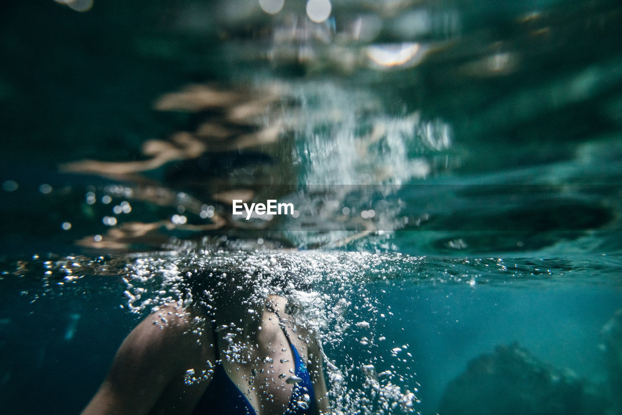 Midsection of woman swimming undersea