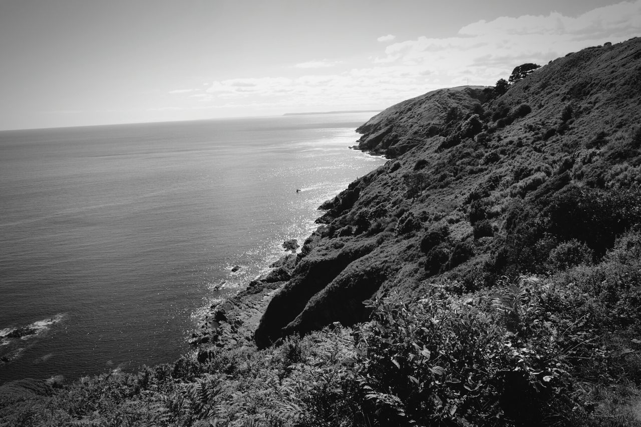 Scenic view of sea and rock formations against sky on sunny day