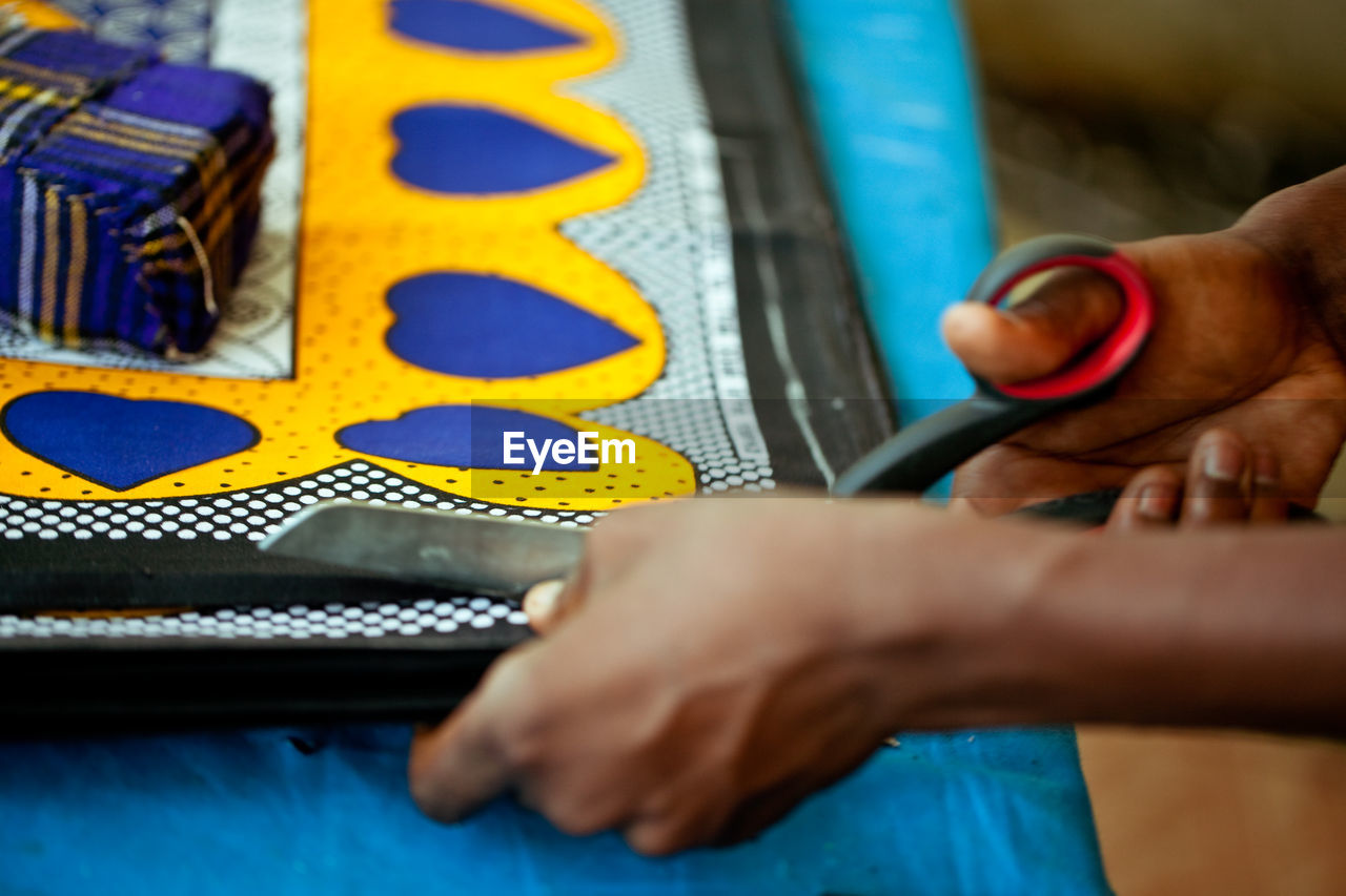 Cropped hand of tailor cutting fabric using scissors