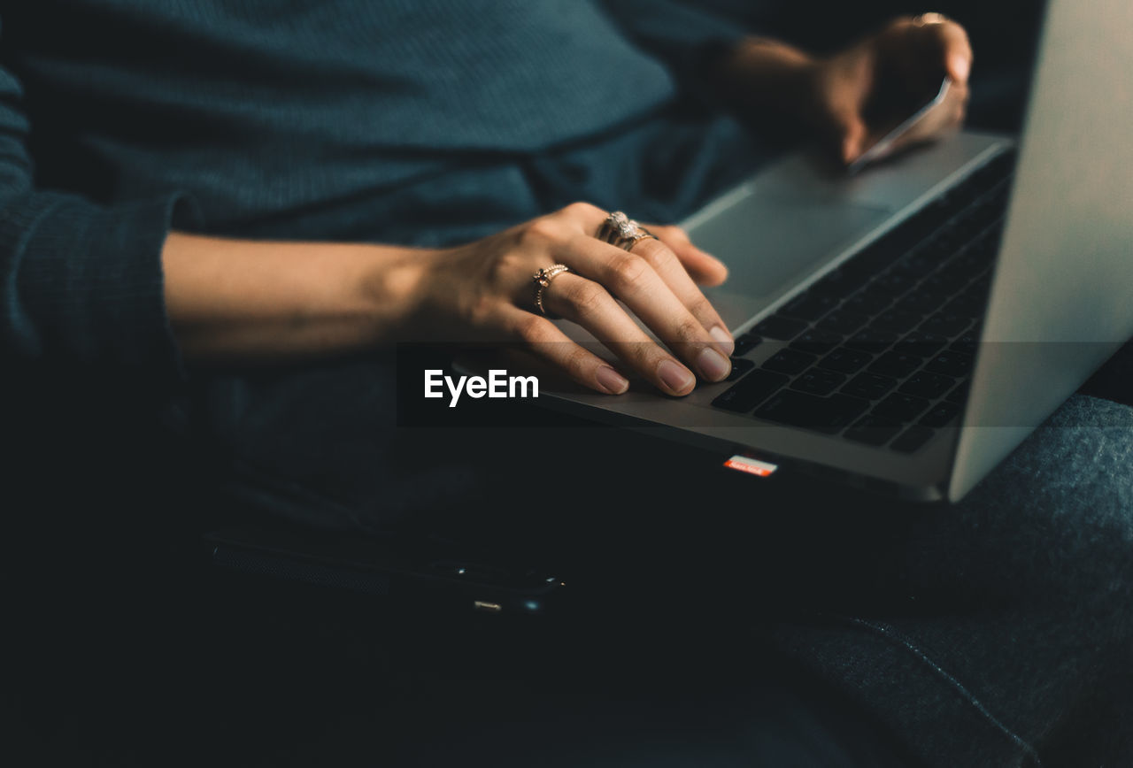 Midsection of woman using laptop on sofa