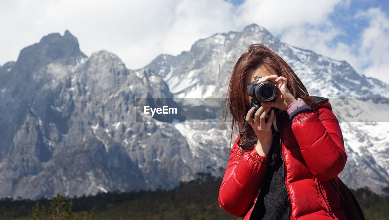 Woman photographing against mountain range