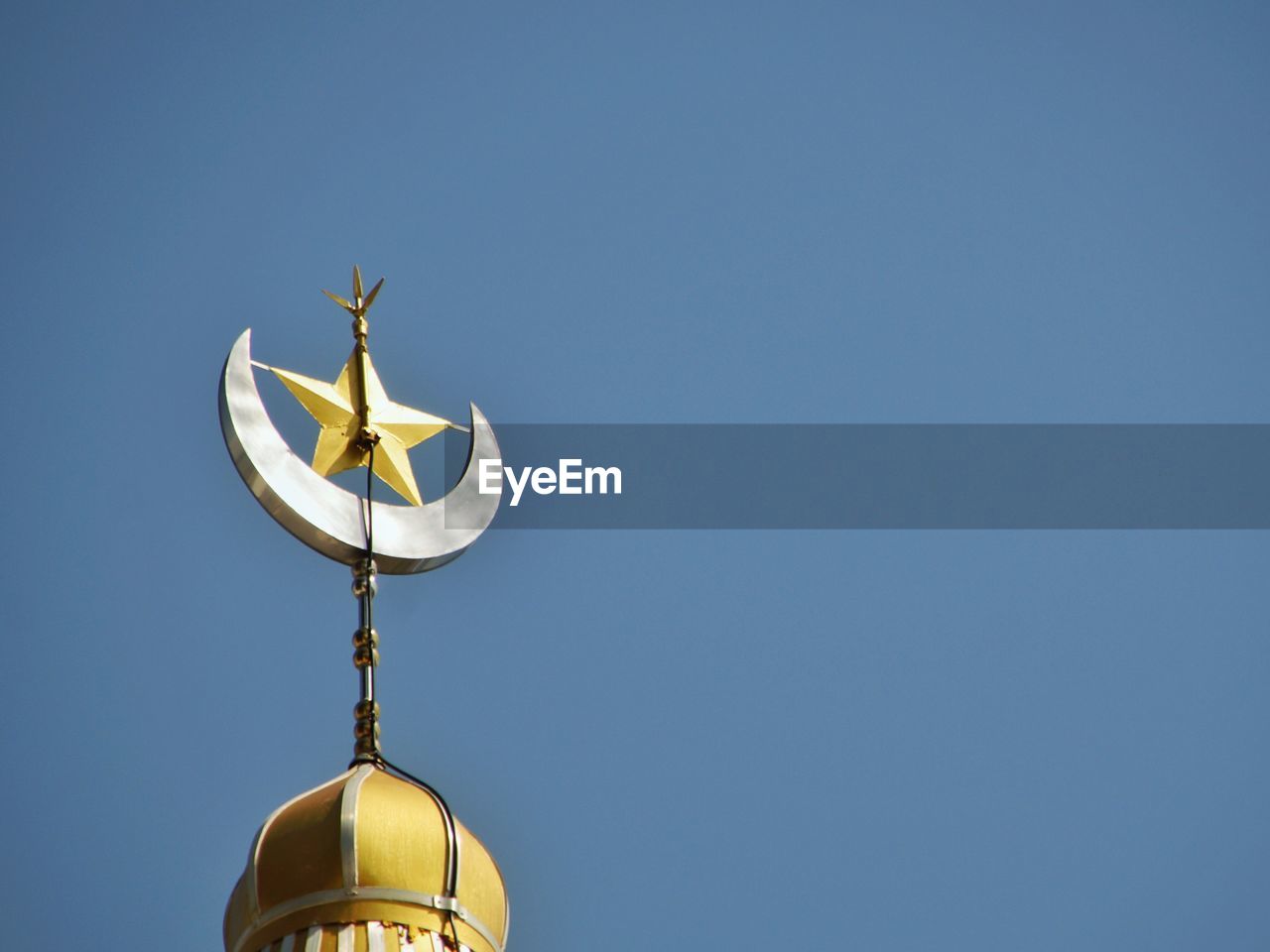 Low angle view of star and crescent on minaret against clear sky