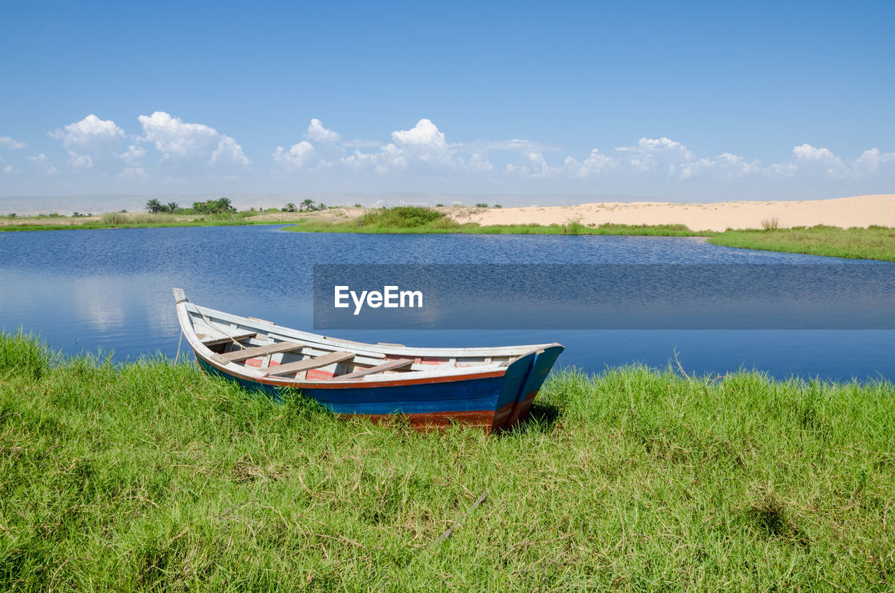 Boat moored in lake against sky