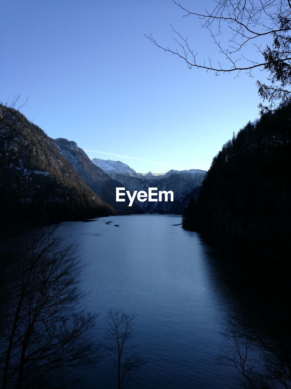 Scenic view of lake and mountains against clear blue sky