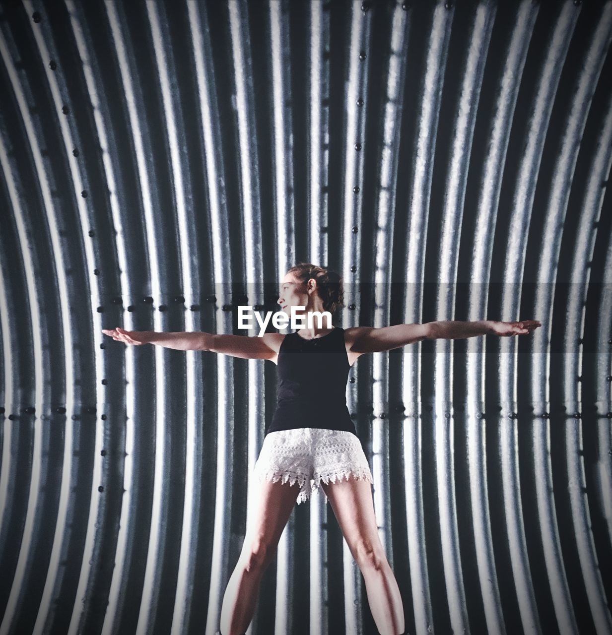 Woman with arms outstretched standing against wall