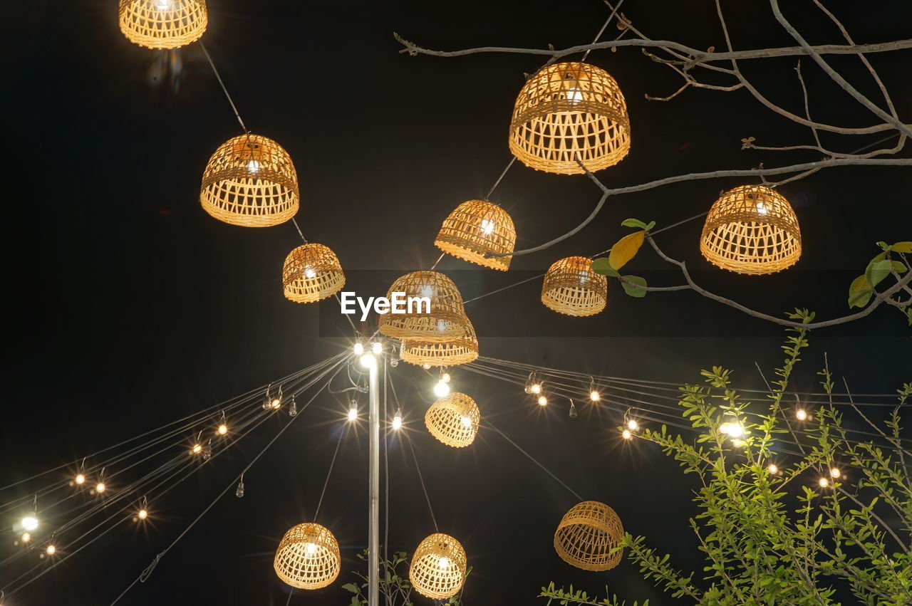 LOW ANGLE VIEW OF ILLUMINATED LANTERNS HANGING AGAINST SKY AT NIGHT