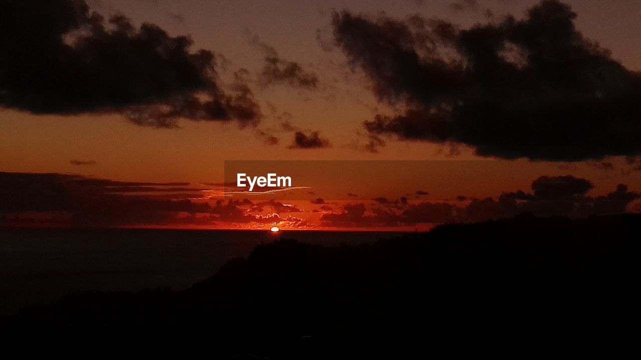 SILHOUETTE OF MOUNTAINS AGAINST DRAMATIC SKY