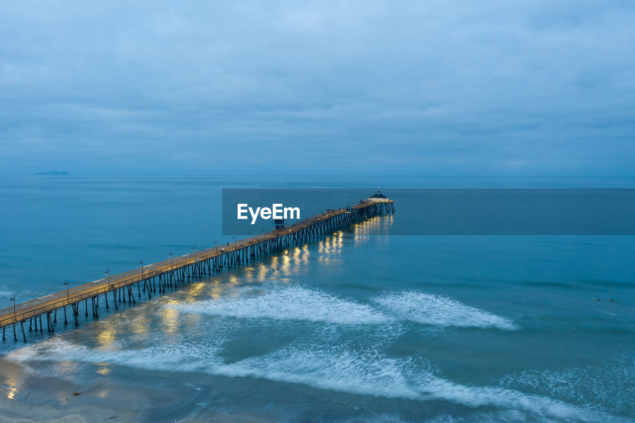 Drone view of imperial beach pier at dawn. waves break against the structure.