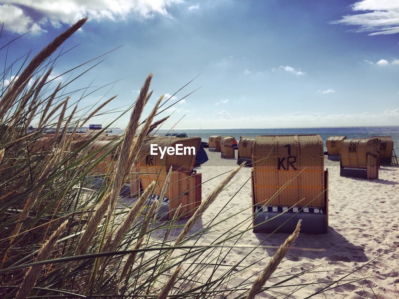 Hooded beach chairs on sand against sky