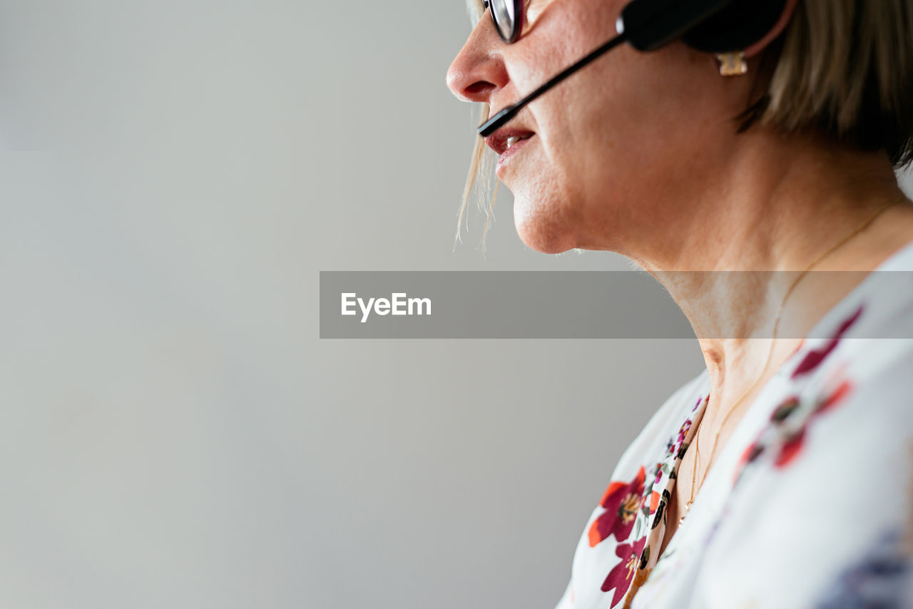 Anonymous middle age female remote specialist in eyeglasses and headset working during telework at home