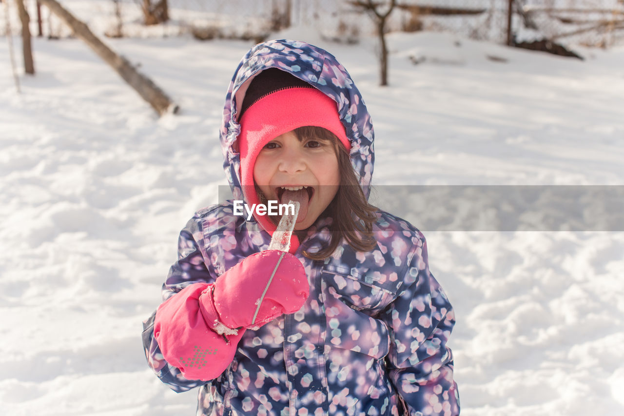 Smiling girl standing on snow during winter