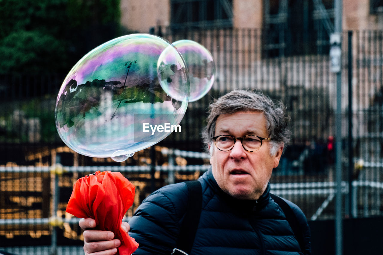 PORTRAIT OF MAN WITH BUBBLES IN PARK