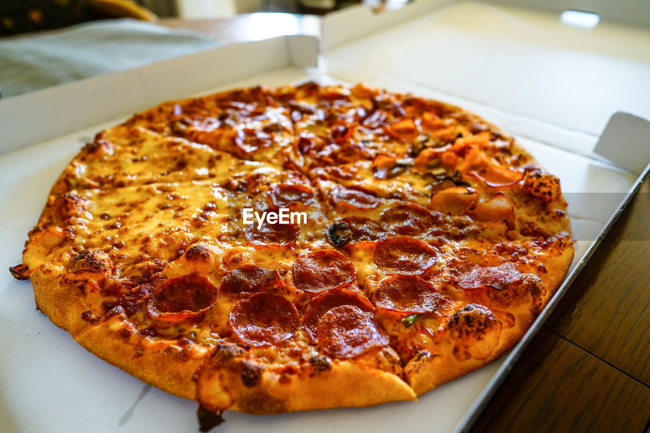 food and drink, food, pizza, fast food, dish, cuisine, freshness, cheese, italian food, unhealthy eating, indoors, no people, dairy, baked, table, close-up, pizza box, high angle view, restaurant, meal, vegetable, business, fast food restaurant