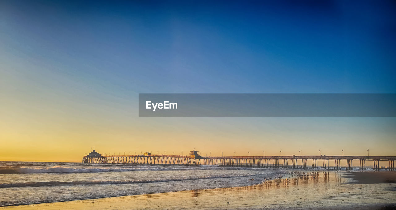 Pier over sea against sky during sunset