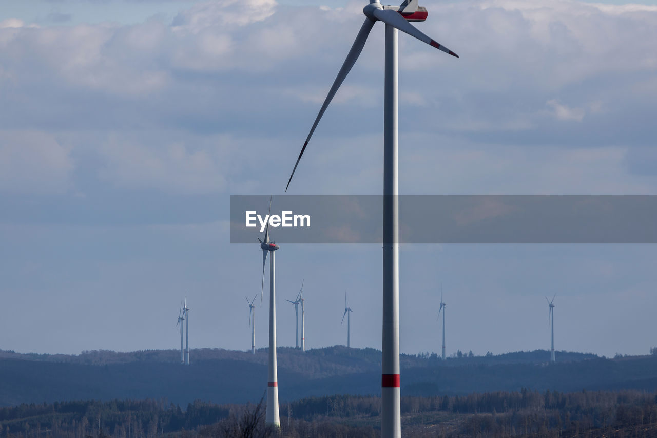 WINDMILLS ON LAND AGAINST SKY