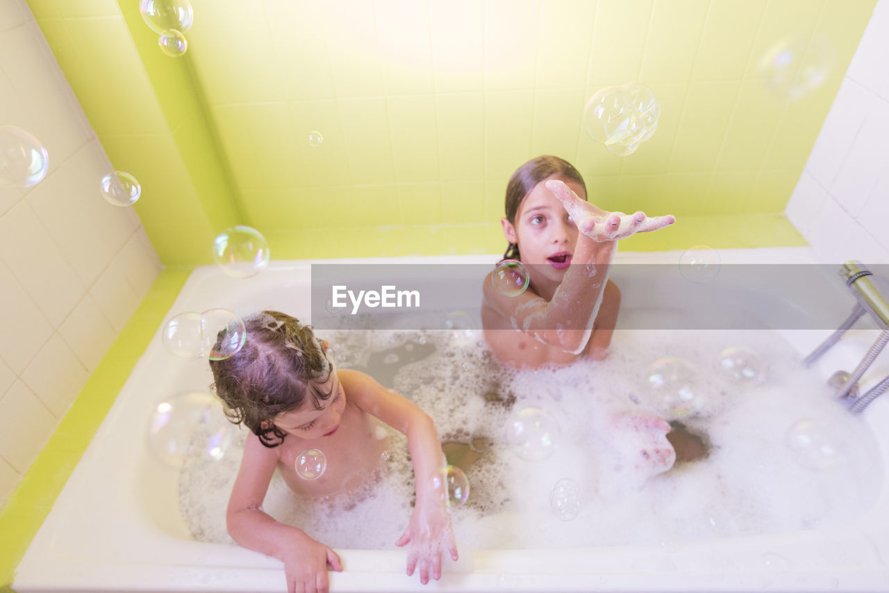 High angle view of siblings playing in bathtub