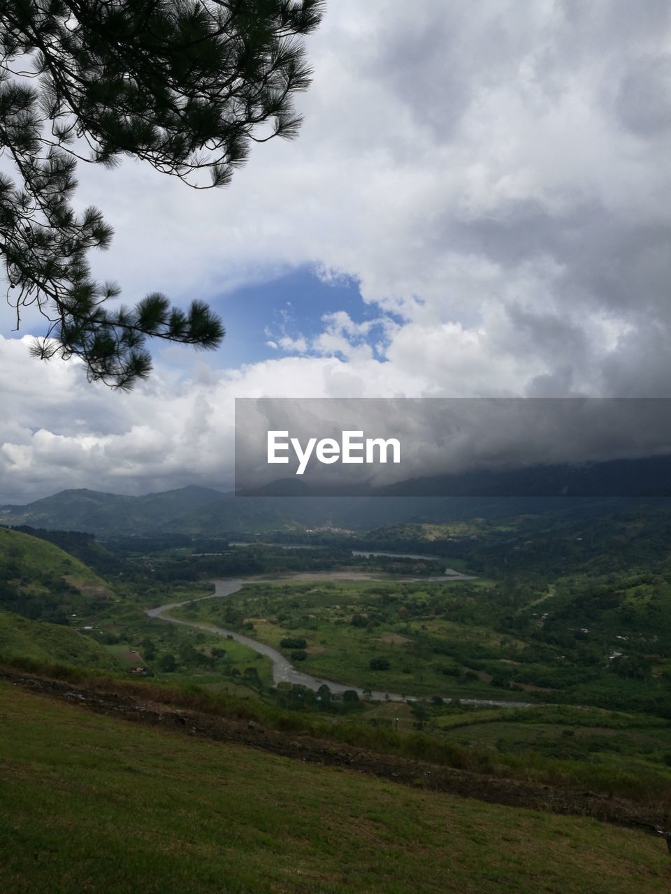 Idyllic shot of green landscape against cloudy sky