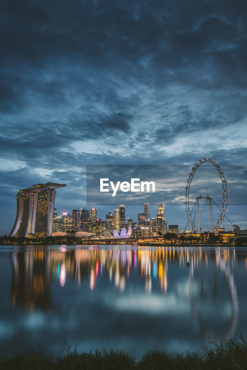 Marina bay sands by bay of water in city at dusk