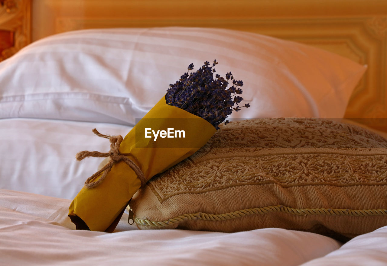 Close-up of lavenders in bouquet by cushion and pillow on bed